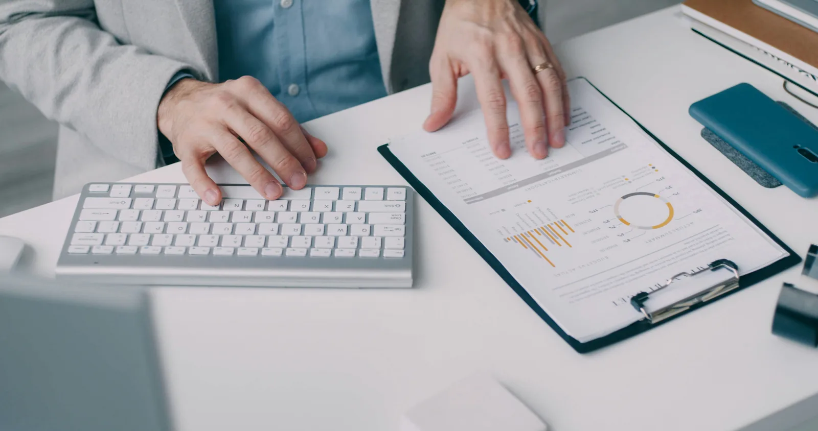 Hands reviewing a report with financial charts beside a keyboard